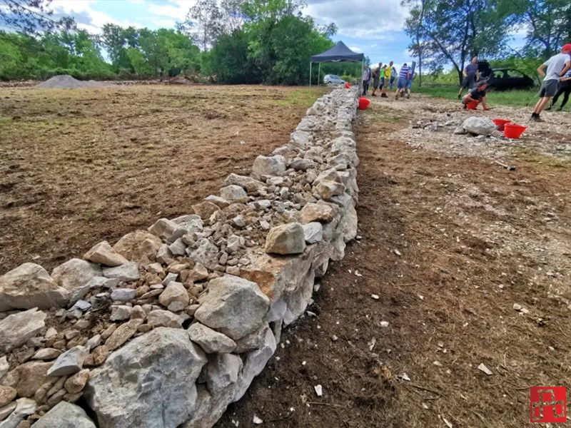 A corporate team rebuilding a traditional dry stone wall in the Croatian countryside